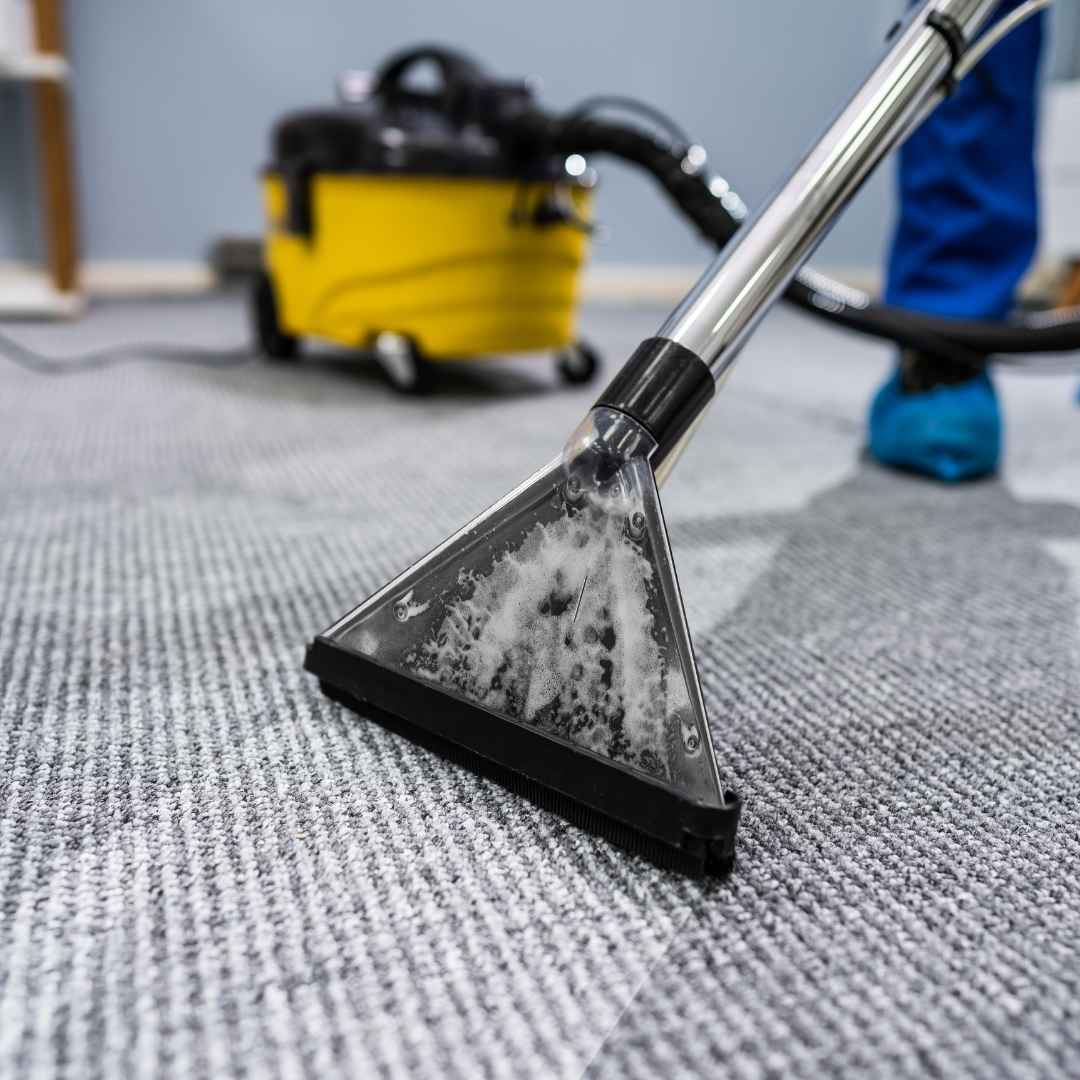 A technician deep-cleaning office carpets with an industrial-grade machine for stain removal and freshness.