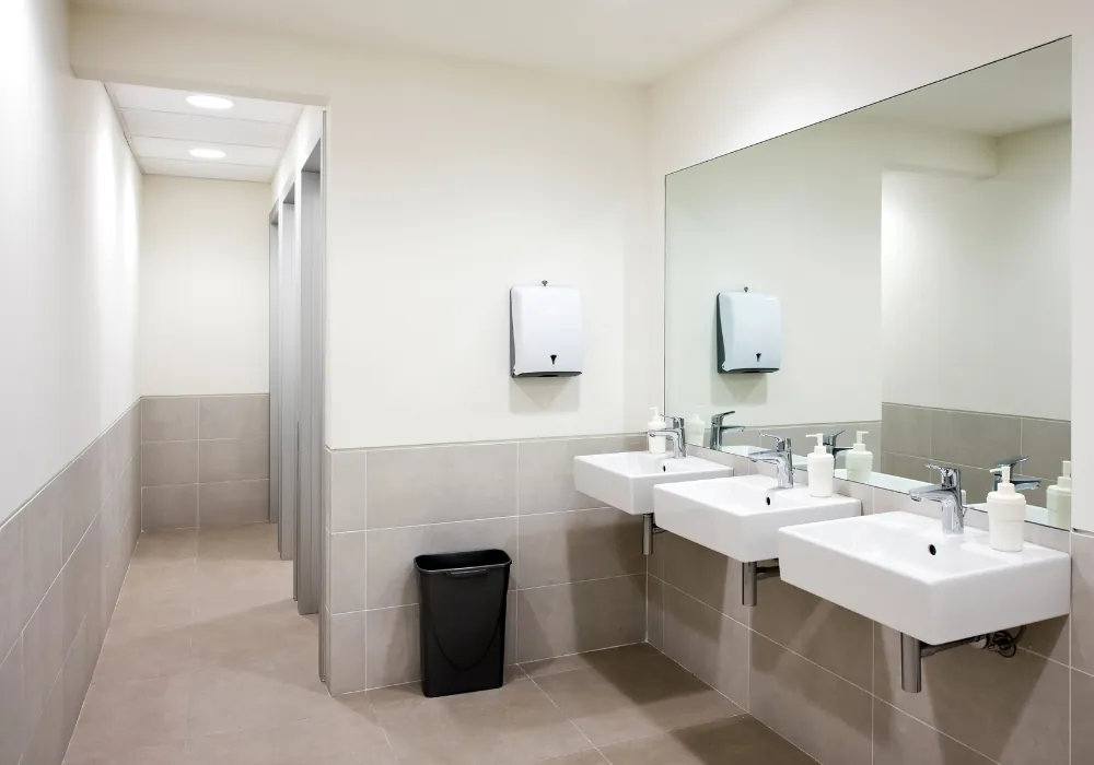 Clean commercial washroom with wall-mounted sinks and stocked soap dispensers